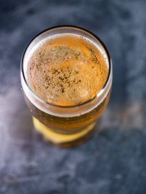 Koyu bir masanın üstünde cam bir manzarada açık bira.