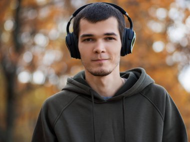 Kulaklıklı, yeşil kapüşonlu genç yakışıklı adam.