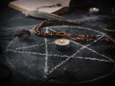 Kara büyü ritüeli, mistisizm ve okültizm. Tahtadaki boyalı pentagram. Mumlar, kurutulmuş otlar ve muskalar.