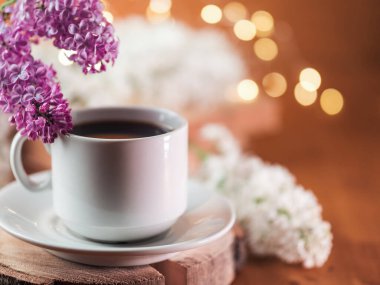 Beyaz kahve fincanı ahşap sehpanın üzerinde çiçek açan leylak dalları ve kopyalama alanı