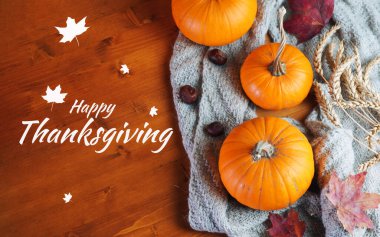 Şükran Günü tebrik kartı manzaran kutlu olsun. Sonbahar balkabakları, örgü eşarp, ahşap bir masada akçaağaç yaprakları.