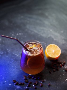 Bir bardak soğuk espresso toniği, portakal suyu ve siyah bir masada bir dilim limon. Serinletici soğuk yaz kokteylleri