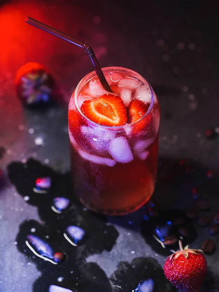 Creative refreshing summer cocktail espresso tonic with lemon and strawberries on a neon colored black table