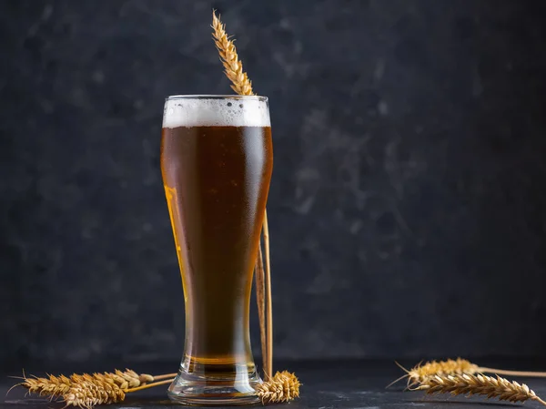Tall glass of light or wheat beer on a black background