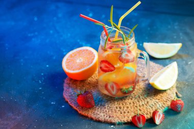 Portakallı, çilekli, limonlu ve biberiyeli detoks suyu. Yaz ferahlatıcı içecek, renkli parlak arka plan