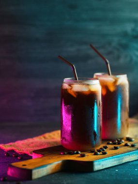 Kremalı ve kavrulmuş kahve çekirdekli uzun bardaklarda soğuk kahve. neon tarzı arka plan ışığı