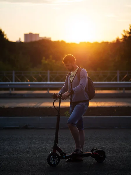 Ein Mann Fährt Bei Sonnenuntergang Mit Einem Elektroroller Ökotransport Der — Stockfoto