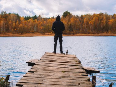 Bir sonbahar ormanının arka planında, köprüde yalnız bir adam. Depresyon, yalnızlık ya da sonbahar turizmi kavramı