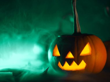 Yeşil dumanlı arka planda el oyması balkabağı feneri ve kopyalama alanı