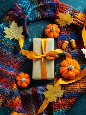 Sonbahar konsepti, Şükran Günü ya da Cadılar Bayramı hediyesi. Üzerinde turuncu bir kurdele ve balkabağı ve akçaağaç yapraklarıyla örülmüş sıcak bir eşarp olan bir hediye kutusu. Cadılar Bayramı indirimi