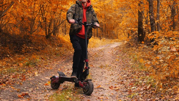 Egy Fiatalember Őszi Erdőben Egy Elektromos Robogón Lovagolj Színes Ősszel — Stock Fotó