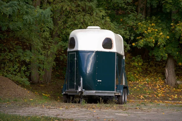 Ağaçların arkasında duran bir at römorku..