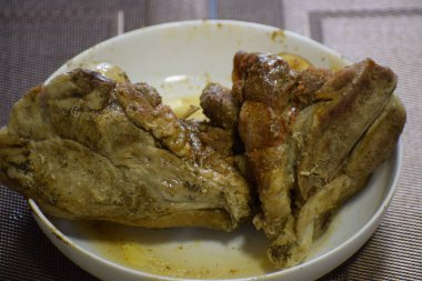 Beyaz tabakta fırında domuz eti ve baharat. Altın kahverengi kabuk ve parlak yüzey iştah açıcı bir görünüm yaratır..