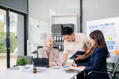 Bir grup genç Asyalı iş adamı modern iş hayatında iş planlarını tartışıyor modern ofis inşaatını tartışıyorlar.