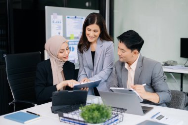 Bir grup genç Asyalı iş adamı modern iş hayatında iş planlarını tartışıyor modern ofis inşaatını tartışıyorlar.