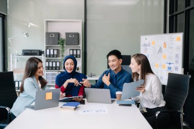 Ofiste yeni bir proje üzerinde çalışırken mutlu iş adamları. Ofiste bir dizüstü bilgisayar ve tablet kullanan bir grup iş adamı