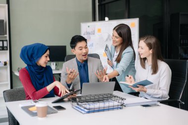 Ofiste yeni bir proje üzerinde çalışırken mutlu iş adamları. Ofiste bir dizüstü bilgisayar ve tablet kullanan bir grup iş adamı