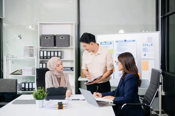 Bir grup genç Asyalı iş adamı modern iş hayatında iş planlarını tartışıyor modern ofis inşaatını tartışıyorlar.