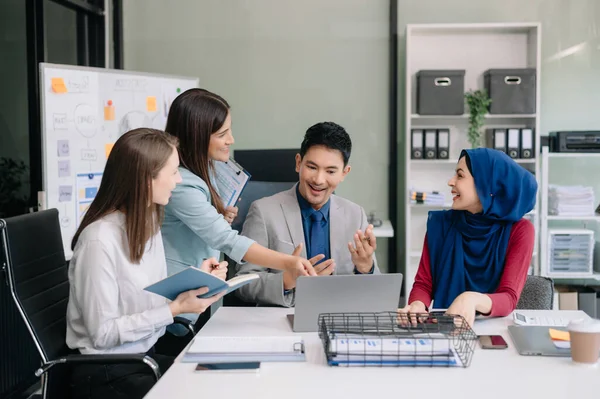 Ofiste yeni bir proje üzerinde çalışırken mutlu iş adamları. Ofiste bir dizüstü bilgisayar ve tablet kullanan bir grup iş adamı