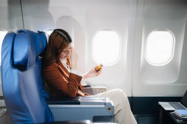 Hayal kırıklığına uğramış bir kadının uçakta kafası ellerindeyken çekilmiş fotoğrafı. Uçakta koltukta oturan Asyalı kadın.