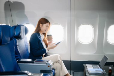 Genç Asyalı yönetici, dijital tablet, dizüstü bilgisayar ve akıllı telefondan birden fazla iş yaparak birinci sınıfta başarılı oluyor. Stil içinde seyahat et, zarafetle çalış.