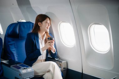 Genç Asyalı yönetici, dijital tablet, dizüstü bilgisayar ve akıllı telefondan birden fazla iş yaparak birinci sınıfta başarılı oluyor. Stil içinde seyahat et, zarafetle çalış.