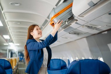 Uçakta bir koltukta oturan ve pencereden dışarı bakan Asyalı kadın seyahate çıkıyor.