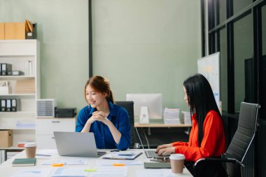 Modern ofis bünyesinde takım çalışması ve iş görüşmeleri yapan iki genç Asyalı profesyonel. 