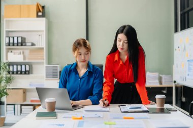 Modern ofis bünyesinde takım çalışması ve iş görüşmeleri yapan iki genç Asyalı profesyonel. 