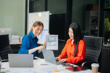 Modern ofis bünyesinde takım çalışması ve iş görüşmeleri yapan iki genç Asyalı profesyonel. 