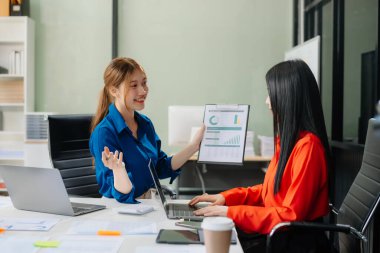Modern ofis bünyesinde takım çalışması ve iş görüşmeleri yapan iki genç Asyalı profesyonel. 