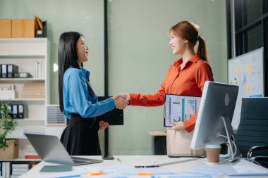 İki Asyalı iş kadını ve erkek modern ofiste tablet dizüstü bilgisayarla çalışma ve planlama stratejisini tartıştılar.