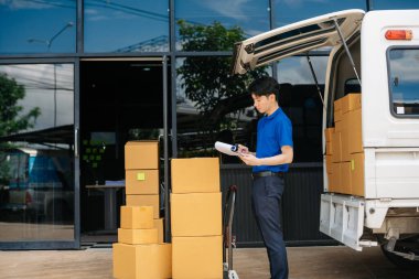 Portrait of Asian courier delivery man searching the address on digital tablet.  near van outside the warehouse. This is a freight transportation and distribution warehouse. 