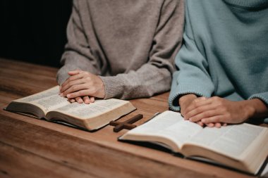 Bir grup Hıristiyan birlikte oturup odalarında açık İncil sayfaları olan ahşap bir masanın etrafında dua ediyorlar. Allah 'ın lütuf ve ihsanını dileyin.