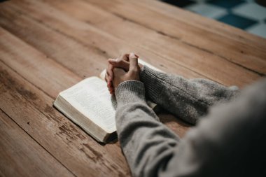 Bir grup Hıristiyan birlikte oturup odalarında açık İncil sayfaları olan ahşap bir masanın etrafında dua ediyorlar. Allah 'ın lütuf ve ihsanını dileyin.