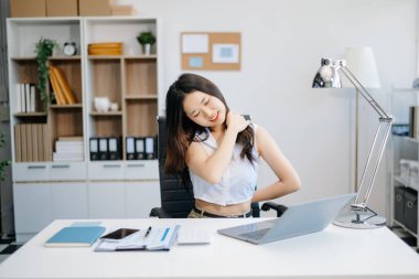 Ofis masasında uzun bir gün geçirdikten sonra boynu ağrıyan Asyalı genç işkadını ofis çalışanı. ofis sendromu kavramı