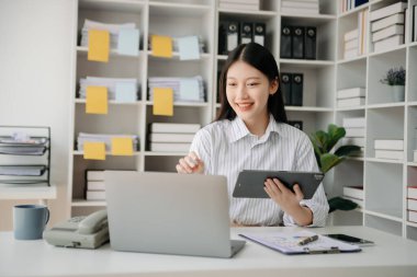 Tablet ve dizüstü bilgisayarda yazan genç ve güzel bir kadın. Çalışan ahşap masa, modern ofis.