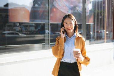 Genç profesyonel iş kadını telefonda konuşurken gülümsüyor, iletişimi, güveni ve modern şirket yaşam tarzını yansıtıyor..