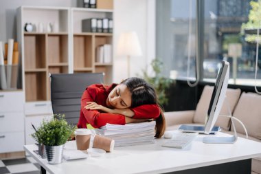 Asyalı kadın migren ağrısı çekiyor. Ofiste dizüstü bilgisayar ve tablet üzerinde çalışırken çok çalışan iş kadını finansör.