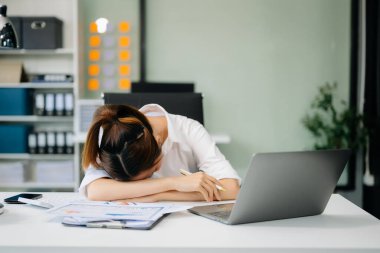 Ofis masasında uzun bir gün geçirdikten sonra boynu ağrıyan Asyalı genç işkadını ofis çalışanı. Ofis sendromu.