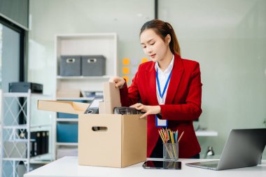 Mutlu ve heyecanlı genç Asyalı kadın ofis çalışanı istifasını kutluyor, kişisel eşyalarını taşıyor. Modern ofiste işi bırakmak, değiştirmek ya da şirket kurmak.