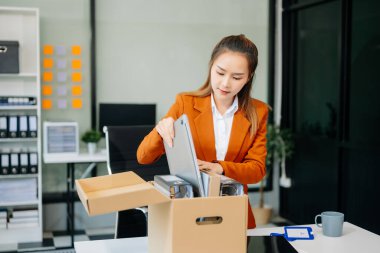Heyecanlı genç Asyalı kadın ofis çalışanı istifasını kutluyor, kişisel eşyalarını taşıyor. Modern ofiste işi bırakmak, değiştirmek ya da şirket kurmak.