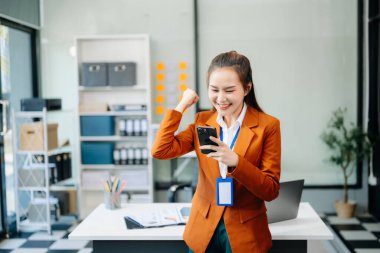 Çalışan not defteri, tablet ve dizüstü bilgisayarla çalışan genç Asyalı iş kadını akıllı telefon, tablet ve dizüstü bilgisayarla konuşuyor. Video arama vergisi, rapor, muhasebe 