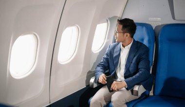 Genç Asyalı yönetici, dijital tablet, dizüstü bilgisayar ve akıllı telefondan birden fazla iş yaparak birinci sınıfta başarılı oluyor. Stil içinde seyahat et, zarafetle çalış.