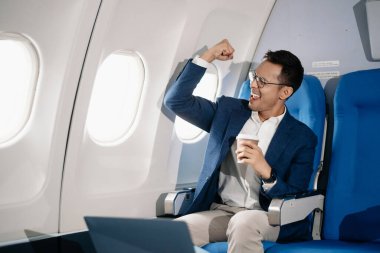 Genç Asyalı yönetici, dijital tablet, dizüstü bilgisayar ve akıllı telefondan birden fazla iş yaparak birinci sınıfta başarılı oluyor. Stil içinde seyahat et, zarafetle çalış.