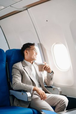 Genç Asyalı yönetici, dijital tablet, dizüstü bilgisayar ve akıllı telefondan birden fazla iş yaparak birinci sınıfta başarılı oluyor. Stil içinde seyahat et, zarafetle çalış.
