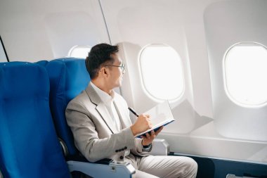 Genç Asyalı yönetici, dijital tablet, dizüstü bilgisayar ve akıllı telefondan birden fazla iş yaparak birinci sınıfta başarılı oluyor. Stil içinde seyahat et, zarafetle çalış.