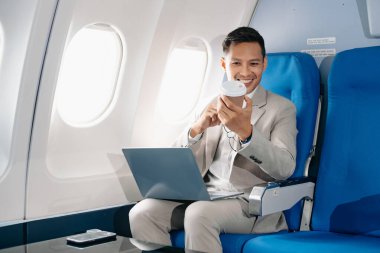 Genç Asyalı yönetici, dijital tablet, dizüstü bilgisayar ve akıllı telefondan birden fazla iş yaparak birinci sınıfta başarılı oluyor. Stil içinde seyahat et, zarafetle çalış.