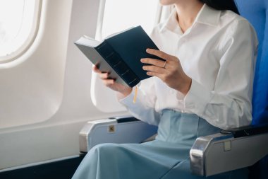 Genç Asyalı yönetici, dijital tablet, dizüstü bilgisayar ve akıllı telefondan birden fazla iş yaparak birinci sınıfta başarılı oluyor. Stil içinde seyahat et, zarafetle çalış.