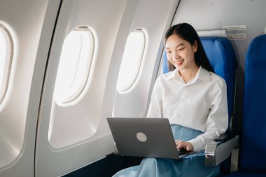 Genç Asyalı yönetici, dijital tablet, dizüstü bilgisayar ve akıllı telefondan birden fazla iş yaparak birinci sınıfta başarılı oluyor. Stil içinde seyahat et, zarafetle çalış.